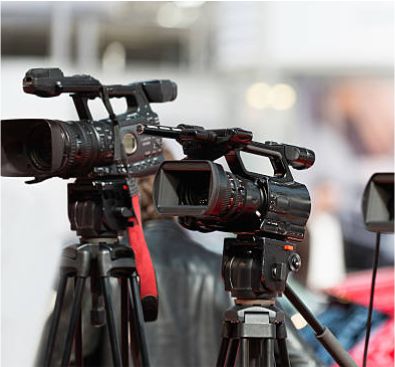 Two professional broadcast video cameras mounted on heavy-duty tripods prepared for a live multi-camera event production.