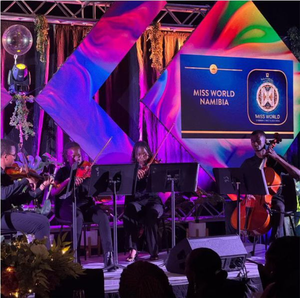 A string quartet performing on stage in front of a colorful Miss World Namibia digital backdrop with professional stage lighting.