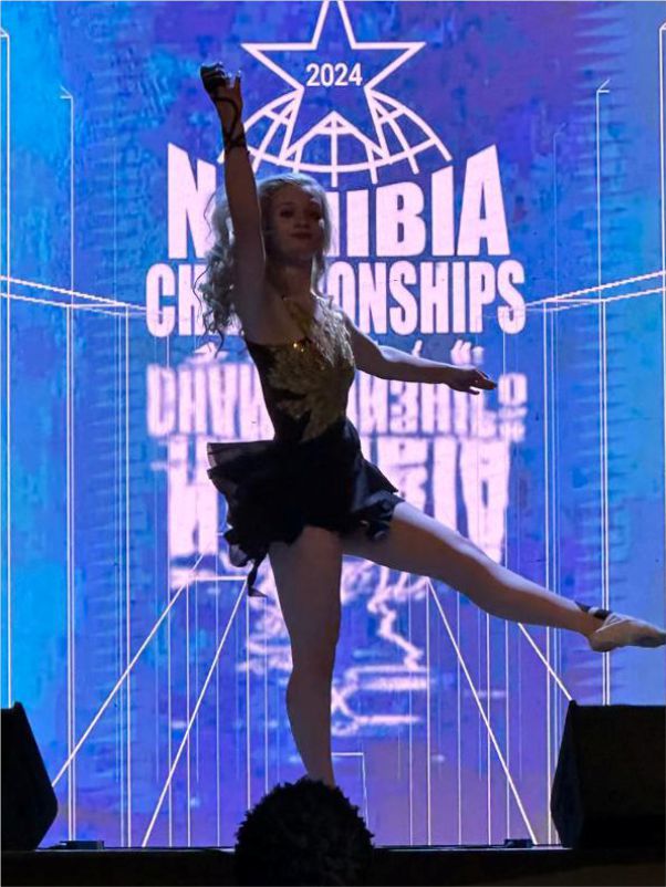 A young female dancer performing on stage at the 2024 Namibia Championships with a blue digital backdrop.