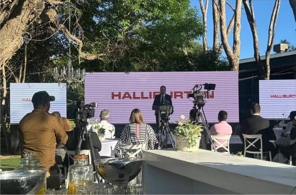 Outdoor corporate event setup for Halliburton with large daylight-visible LED screens and professional video camera filming for a live audience.