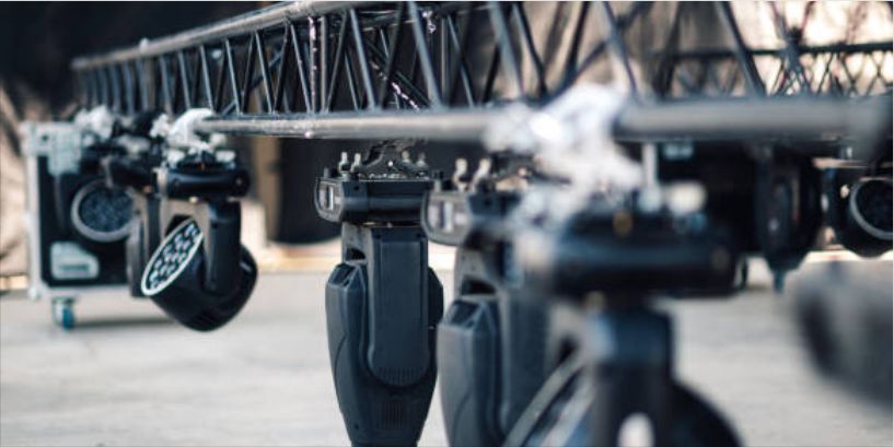 Professional stage lighting rig with several black moving head LED fixtures attached to a metal truss.